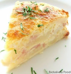 a piece of quiche on a white plate with green garnish and parsley