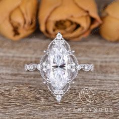 an engagement ring with a pear shaped diamond surrounded by smaller pears on a wooden table