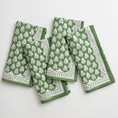 four green napkins with white designs on them