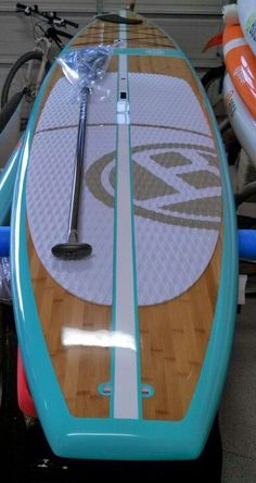 a surfboard is sitting on top of a stand up paddle board in a garage