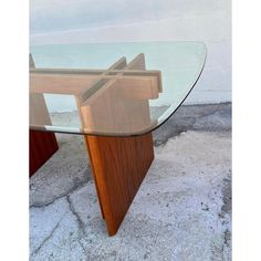 a glass table with wooden legs on concrete ground