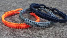 three different colored bracelets sitting on top of a gray and orange cloth covered floor