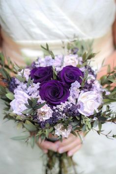 a bride holding a bouquet of purple and white flowers in her hands with the words, large bridal & roses