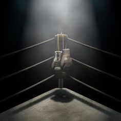 a boxing ring with two gloves hanging from the ropes and one light shining on it