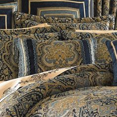 a bed covered in blue and gold comforter set with pillows on top of it