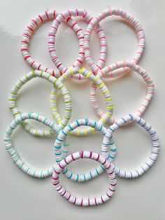 six bracelets with different colors and sizes on a white surface, one is in the middle