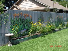 a fence with flowers painted on it in front of a house