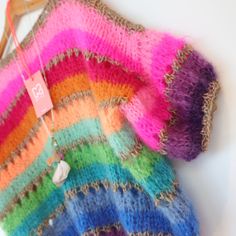 a multicolored sweater hanging from a wooden hanger