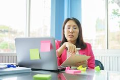 a woman sitting in front of a laptop computer on top of a table with sticky notes