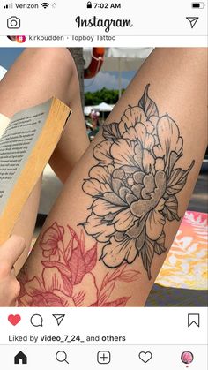 a woman's leg with flowers on it and an open book in front of her