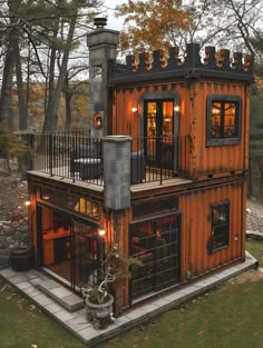 a house made out of shipping containers with lights on the windows and balconies