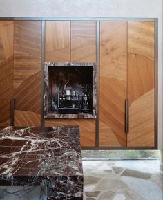 a marble counter top in front of wooden cabinets with doors open to reveal a bottle of perfume