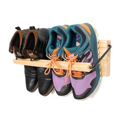 three pairs of shoes are hanging on a wooden rack with shoelaces attached to them