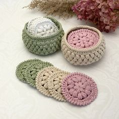 three crocheted baskets sitting on top of a white table next to pink flowers