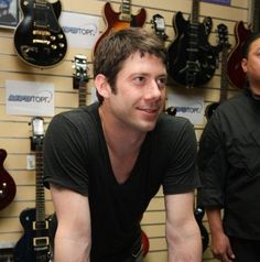 a man is sitting in front of guitars