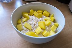 a bowl filled with oatmeal topped with sliced mango