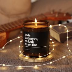 a lit candle sitting on top of a table next to a string of lights and a guitar