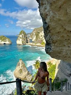 a woman standing on top of a cliff next to the ocean