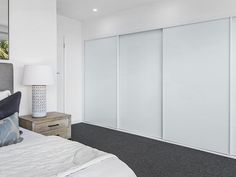 a bedroom with white sliding doors and carpeted flooring in front of the bed