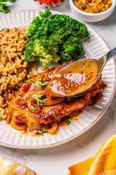 a white plate topped with meat, rice and broccoli next to other foods