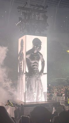 a man standing on top of a giant screen in the middle of a crowd at a concert