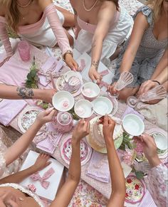 a group of women sitting around a table with plates and cups on it's sides