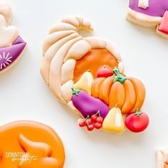 decorated cookies are arranged in the shape of pumpkins, squash and other fruits on a white surface