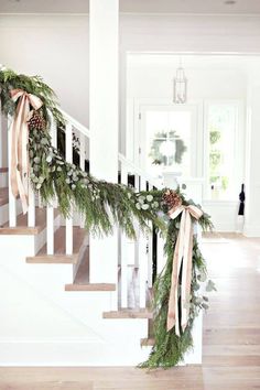 the stairs are decorated with greenery and pine cones for garlands on each handrail