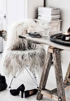 a white chair sitting next to a wooden table with shoes on it and a bottle of wine