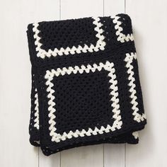 a black and white crocheted blanket sitting on top of a wooden floor