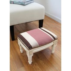 a white bench with a pink and brown striped cushion on it next to a wooden floor