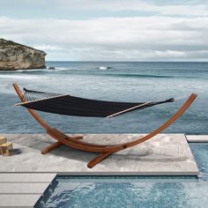 a hammock sitting on top of a wooden stand next to a swimming pool