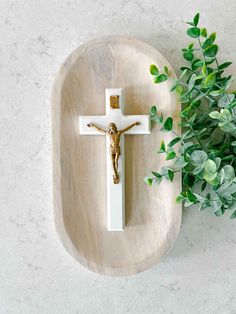 a wooden cross with a plant in the corner next to it on a marble surface