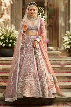 a woman in a pink lehenga standing on steps