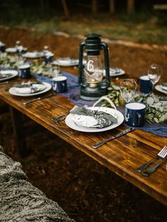 the table is set with plates, silverware and napkins for an outdoor dinner