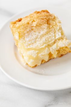 a piece of cake on a white plate with powdered sugar and icing over it