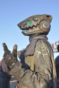 a man dressed as a creature with goggles and gloves holding something in his hand