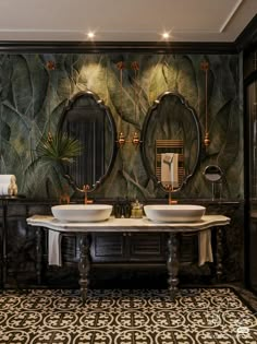 a bathroom with two sinks and mirrors in front of a green leafy wallpaper