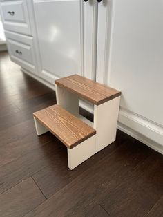 two step stools sitting on the floor in front of a kitchen counter top with white cabinets