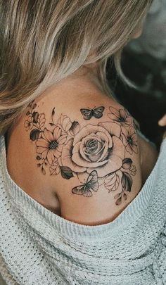 the back of a woman's neck with flowers and butterflies tattooed on her chest