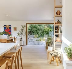 a living room filled with lots of furniture and plants on top of wooden shelves next to a doorway