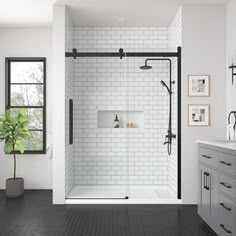 a bathroom with black and white tile flooring, a walk - in shower and sink