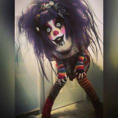 a creepy doll with purple hair and striped stockings is standing in front of a wall