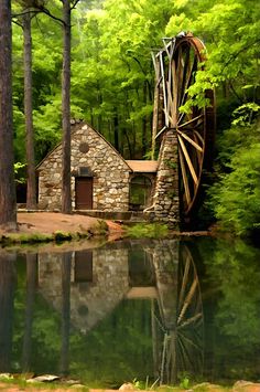 an old mill sits in the middle of a lake surrounded by green trees and water