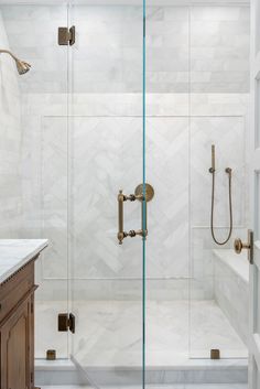 a walk in shower sitting next to a white sink and wooden cabinet under a mirror