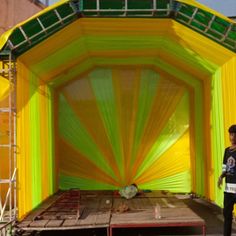 a man standing on top of a stage under a yellow and green tent covered in tarp