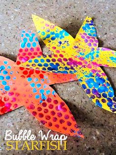 three colorful paper starfishs sitting on top of a cement floor next to each other