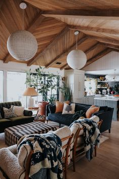 a living room with couches, chairs and lamps on the ceiling in front of windows