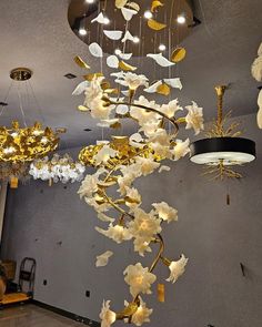 a chandelier hanging from the ceiling with white flowers and gold leaves on it