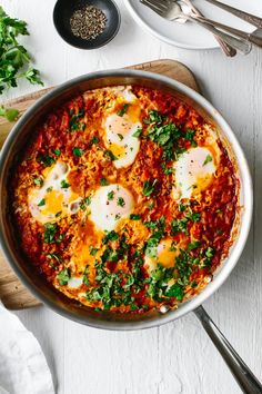 an egg dish in a skillet with parsley on top and other ingredients around it